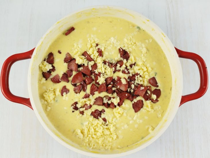 Calabresa e parmesão colocados na panela.