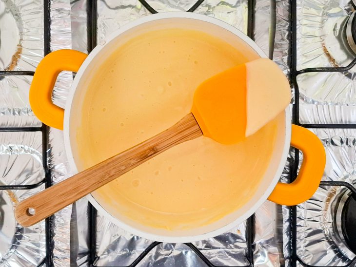 Ingredientes ao fogo, misturados e com textura cremosa.