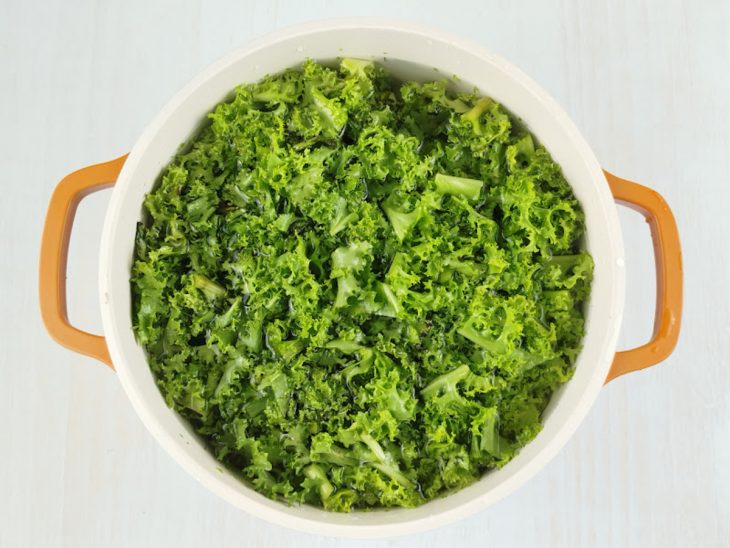 Chicória sendo rapidamente submersa em água quente para branqueamento.