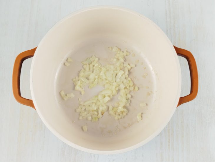 Cebola refogando na panela até murchar.
