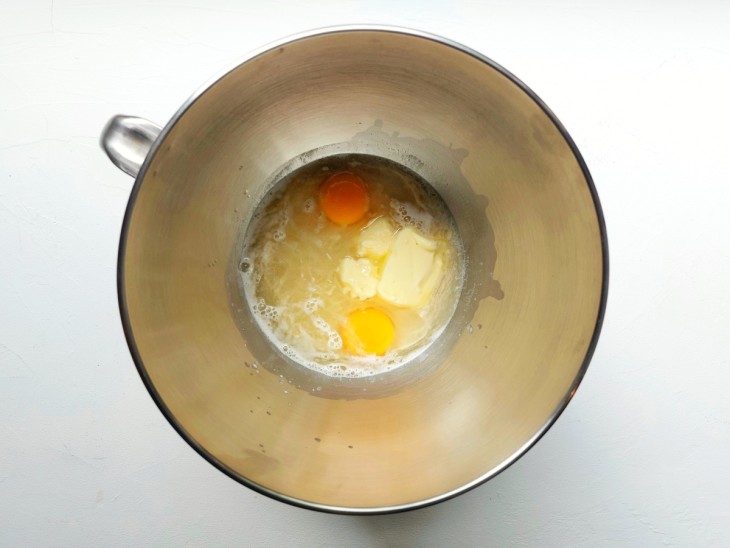 Um recipiente com a água, fermento biológico seco, manteiga, ovo e sal.