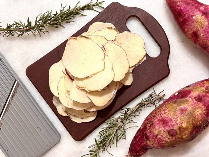 Rodelas de batata-doce fatiada em cima de uma tábua.