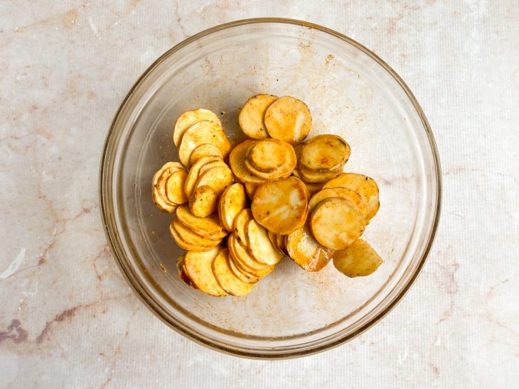 Numa tigela, os chips de batata temperados com azeite, páprica doce, sal e pimenta-do-reino.