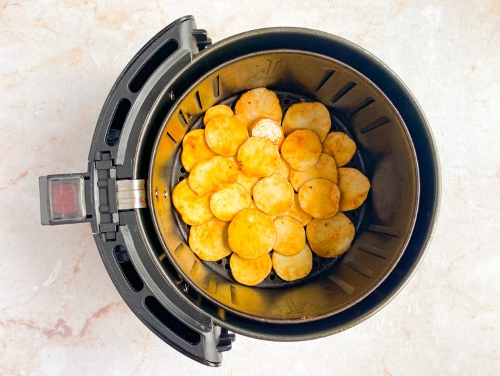 No cesto da air fryer, os chips estão distribuídos.