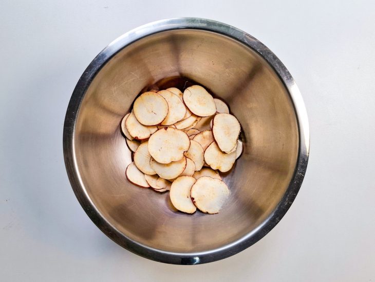 Batata-doce fatiada em lâminas finas numa tigela redonda.