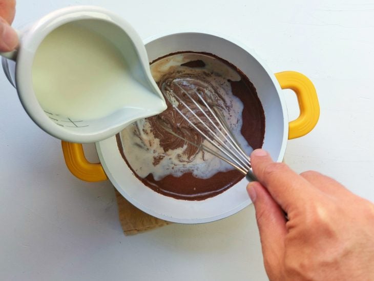 Uma panela contendo a mistura de creme de leite, chocolate em pó, leite em pó e leite.