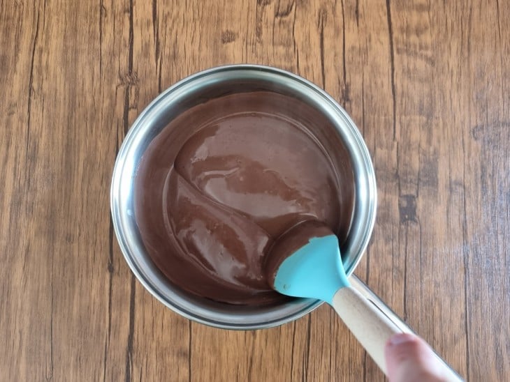 Espátula mostrando a consistência do chocolate quente na panela.
