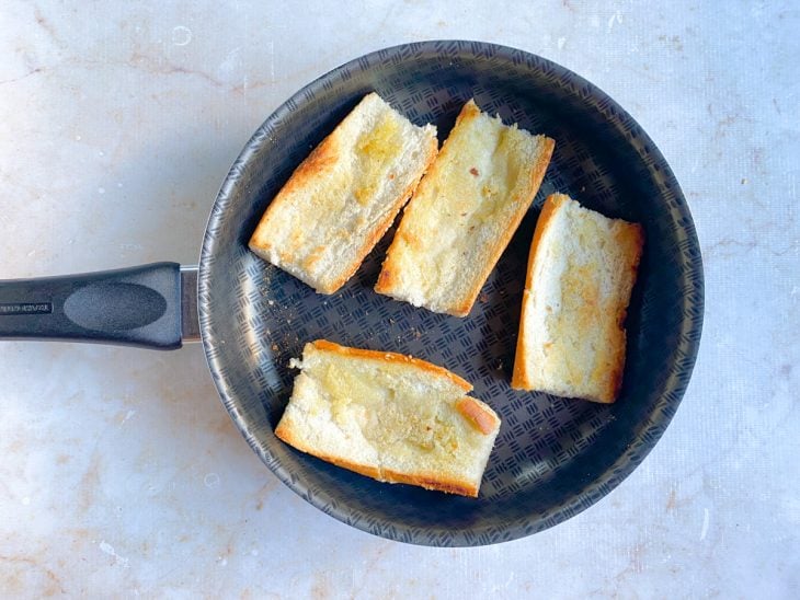 Pães fritos com manteiga na frigideira.