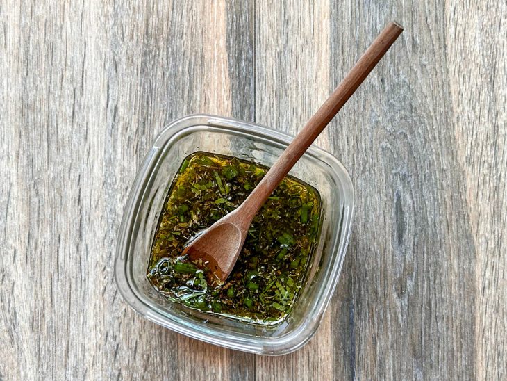 Molho chimichurri preparado dentro de um pequeno pote de vidro.