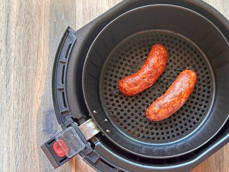 Gomos de linguiça grelhados dentro do cesto da airfryer.