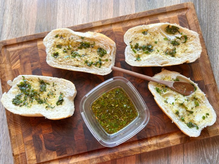 Camada de molho chimichurri espalhada sobre os pães.