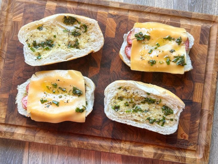 Fatias de linguiça e queijo prato adicionados sobre os pães.