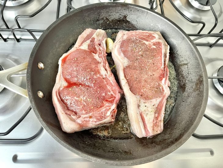 Uma frigideira fritando duas chuletas.