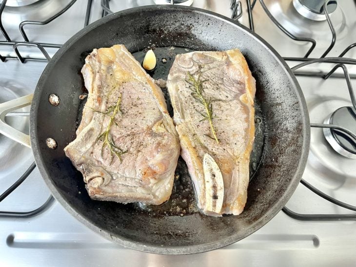 Uma frigideira fritando duas chuletas.