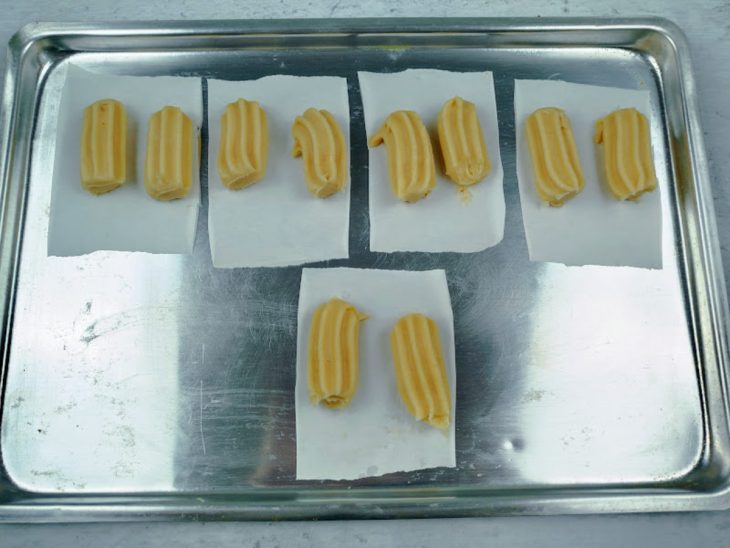 Massa de churros sobre pedaços de papel-manteiga.