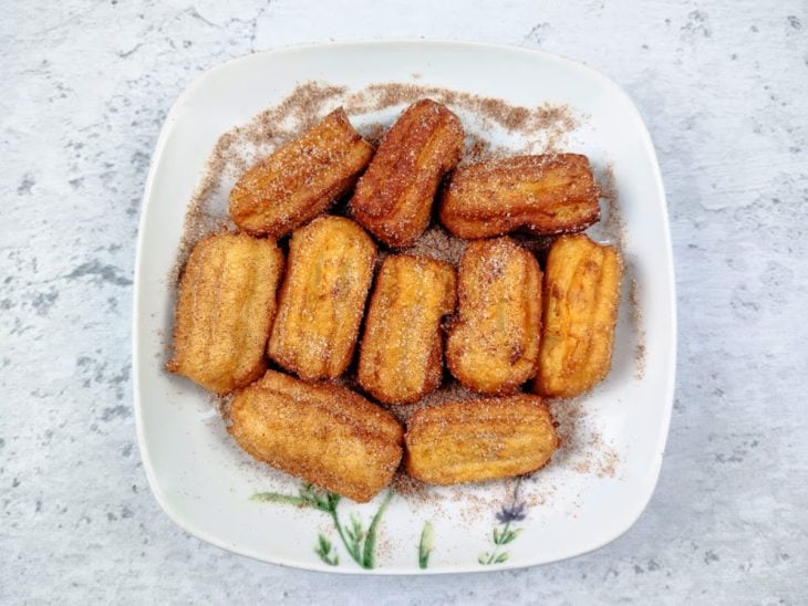 Um prato com churros polvilhado com canela e açúcar.