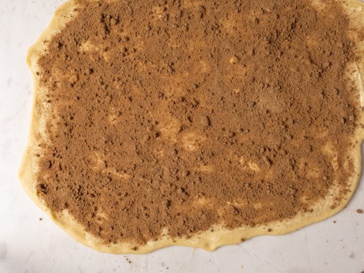 Massa aberta com recheio de canela e açúcar espalhado.