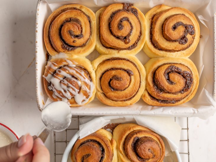 Cobertura sendo colocada nos cinnamon rolls.