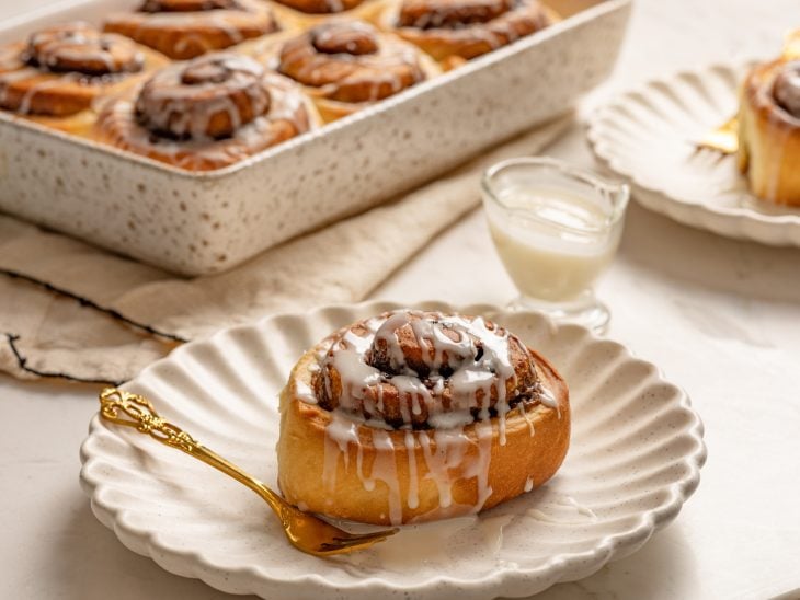 Cinnamon rolls servido em um prato com os outros servidos na travessa.