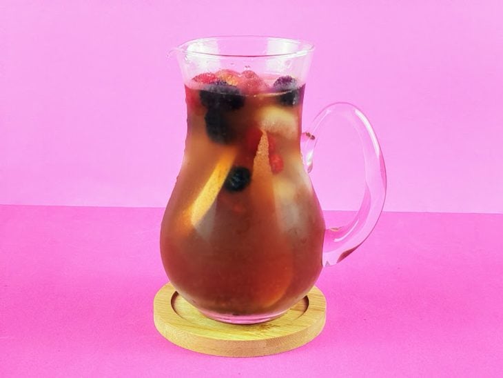 Bebida em uma jarra com frutas e gelo adicionados.