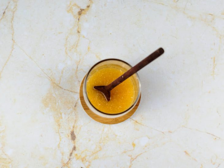 Suco de laranja, gengibre ralado e mel misturados em um copo de vidro.