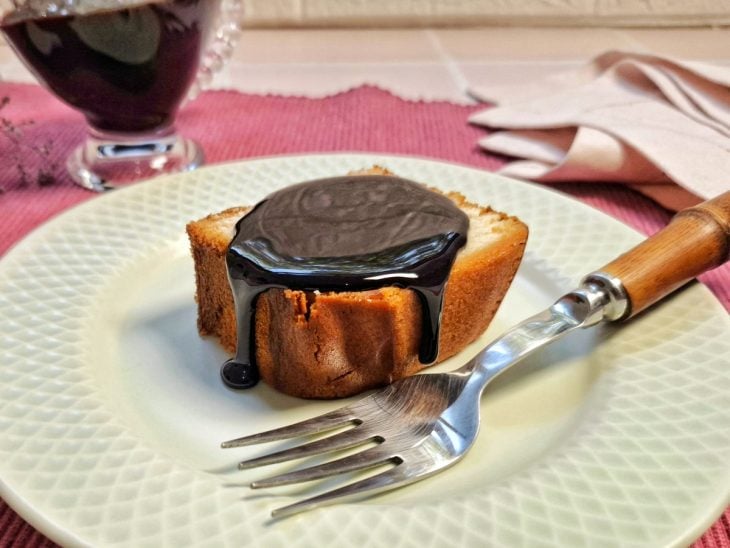 Cobertura de chocolate sobre uma fatia de bolo em um prato.