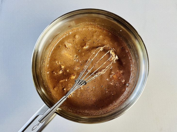 Ingredientes misturados em uma panela com auxílio de um fouet (batedor de arame).