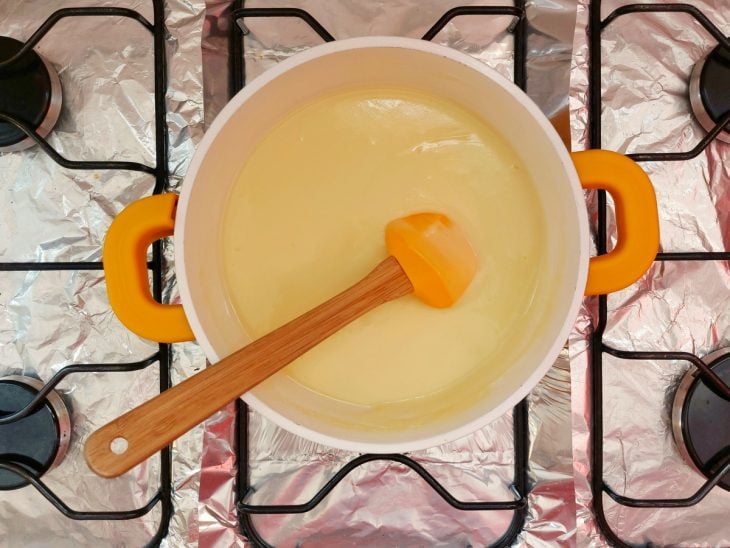 Uma panela com a mistura de leite condensado, leite em pó, creme de leite e manteiga.