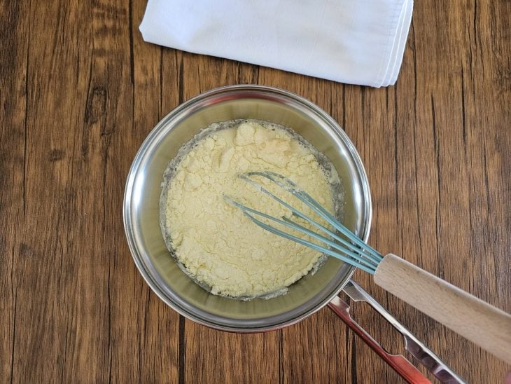 Um fouet e uma panela com açúcar, leite Ninho, leite e margarina.