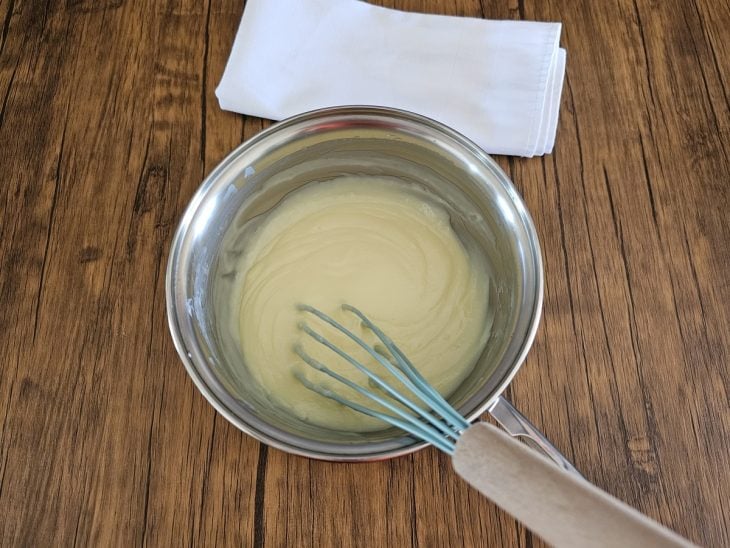 Um fouet e uma panela com a mistura da cobertura.