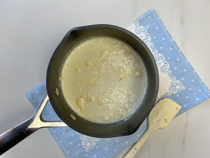 Uma panela contendo a mistura de leite condensado, leite em pó, creme de leite, leite e manteiga.