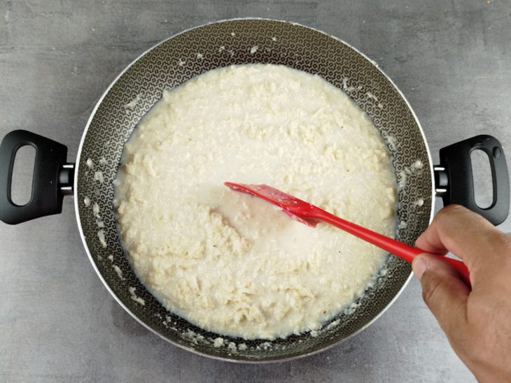 Cocada cozinhando no fogão, sendo mexida para não grudar.