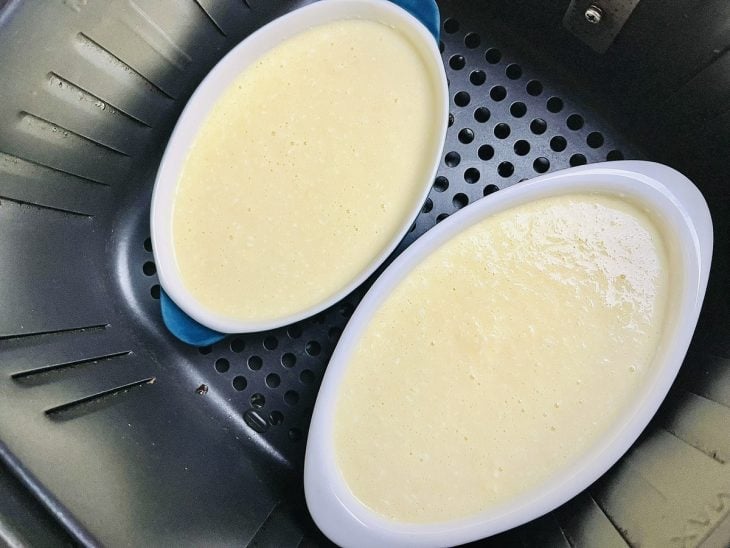 Mistura de cocada cremosa em refratários de porcelana dentro do cesto da air fryer.