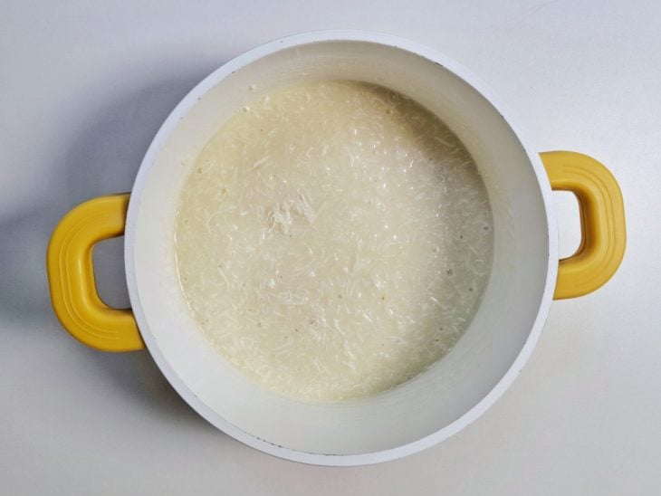 Uma panela com leite condensado, açúcar refinado e coco ralado.