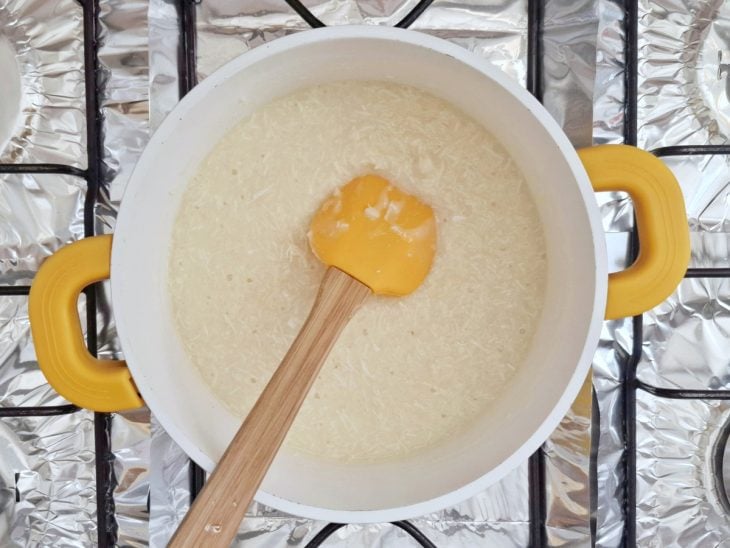 Uma panela com a cocada ao fogo e uma espátula.