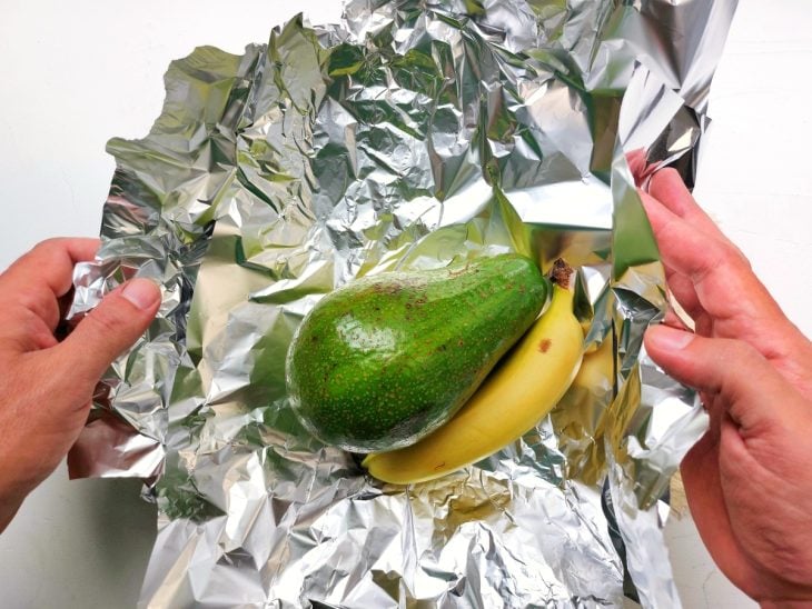 Um papel alumínio contendo um abacate e uma banana.