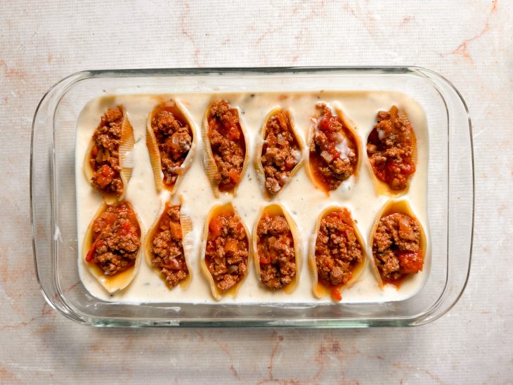 Refratário com uma camada do molho branco e os conchigliones recheados.