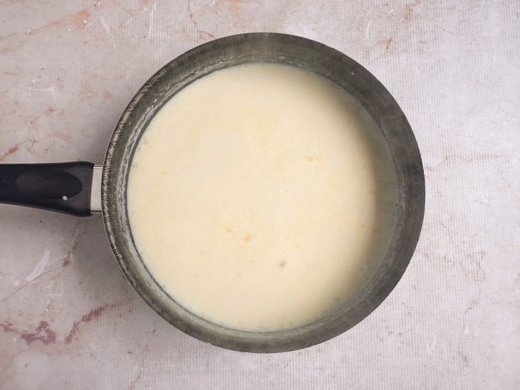 Leite sendo adicionado e misturado até formar um creme liso.