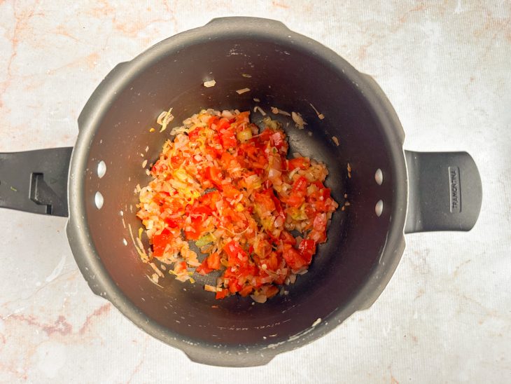 Alho-poró e tomate sendo refogados junto aos temperos.