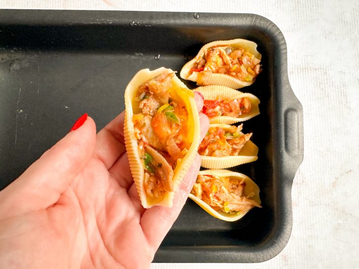 Conchiglione sendo recheado cuidadosamente com o frango.