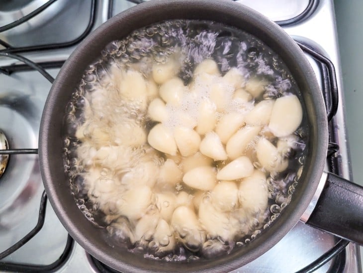 Uma panela com água fervendo e dentes de alho.