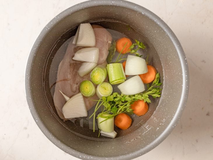 panela de pressão com água e os ingredientes do consomê de frango