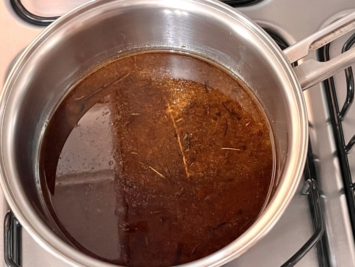 Uma panela com caldo de carne temperado.