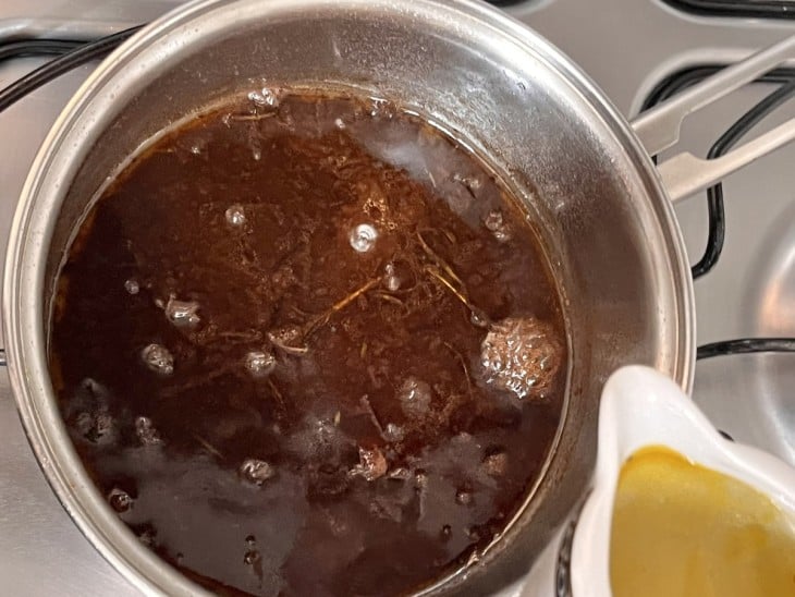 Uma panela com caldo de carne temperado.