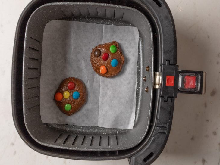 Cookies modelados e acomodados na Air Fryer sobre papel-manteiga.