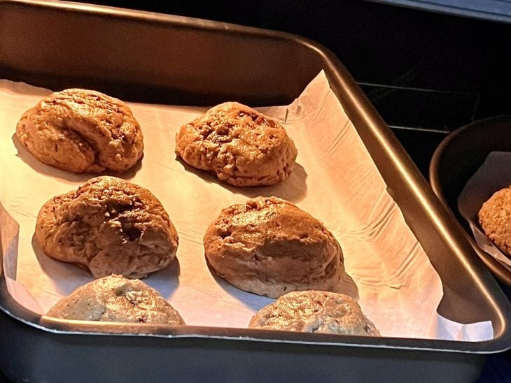 Uma forma forrada contendo 6 cookies sendo assados.