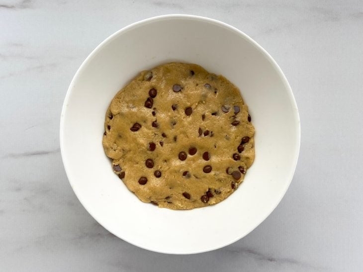 Um recipiente contendo a massa do cookie com gotas de chocolate.