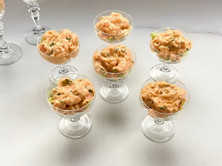 Taças com tiras de alface cobertas com creme de camarão.