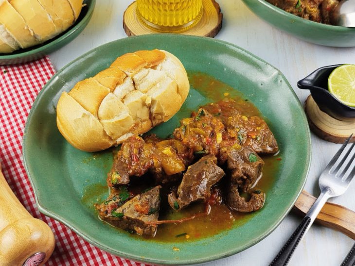 Carne pronta, servida em prato com pão francês em fatias.