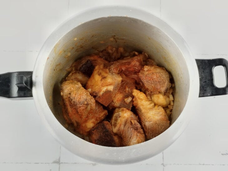 Alho, cebola, colorau e sal sendo misturados e refogados junto com a costela dourada.